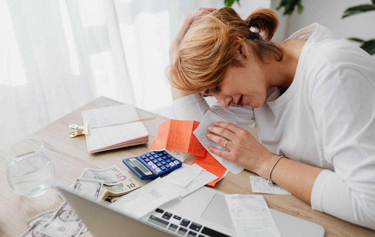 Pessoa preocupada diante de contas e calculadora sobre a mesa