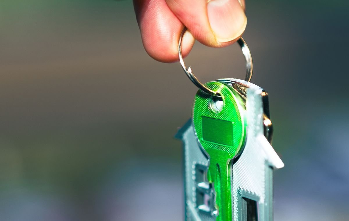 Mão segurando a chave de uma casa, representando a regularização do imóvel